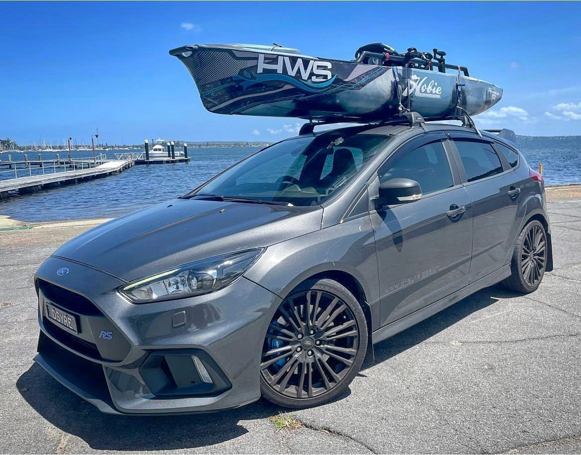 A Hobie Pro Angler 12 fishing kayak strapped to the roof racks of a Ford Focus hatch for transport